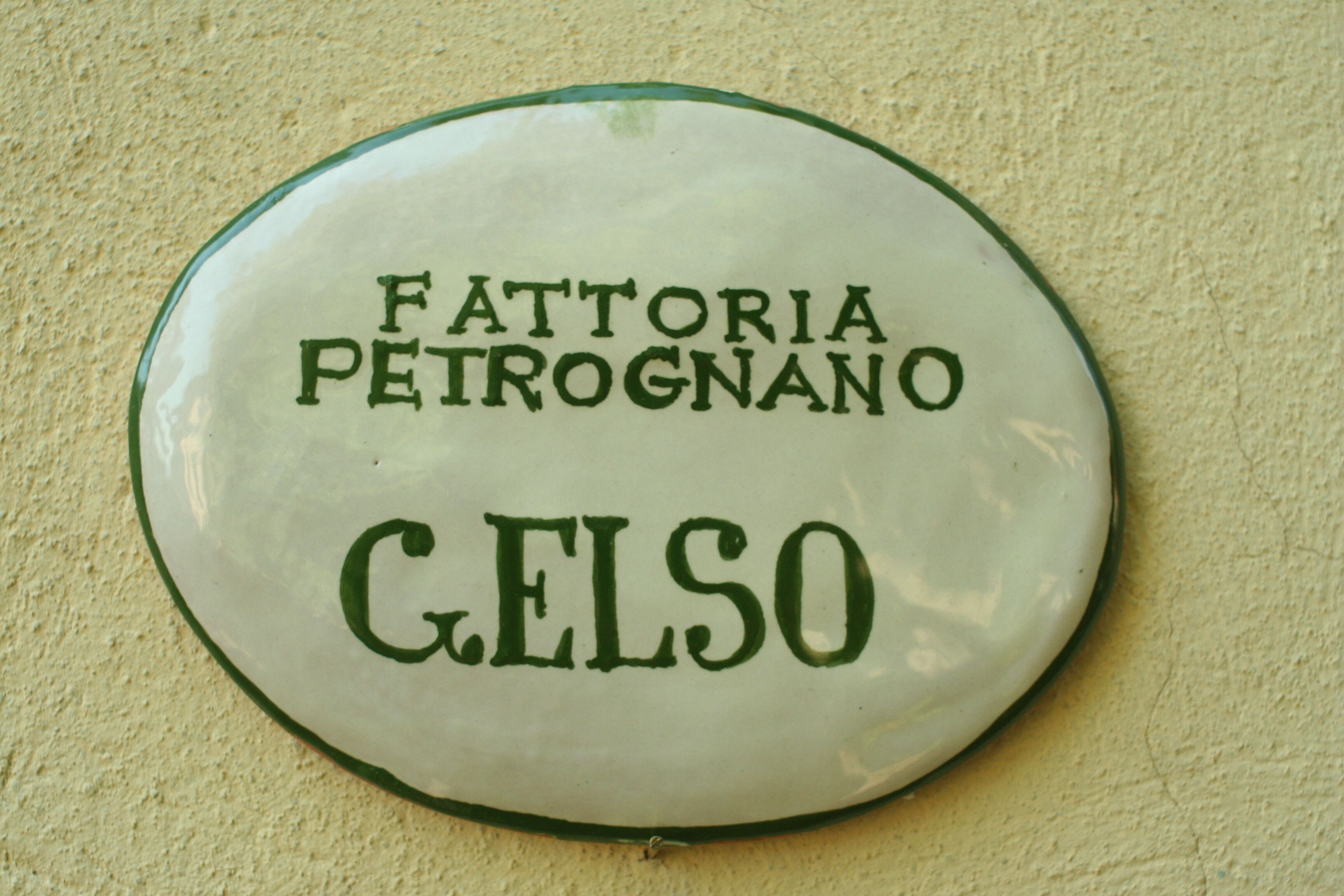 A round, white ceramic plate with the inscription "Fattoria Peirognano" and "GELSO" in green lettering.