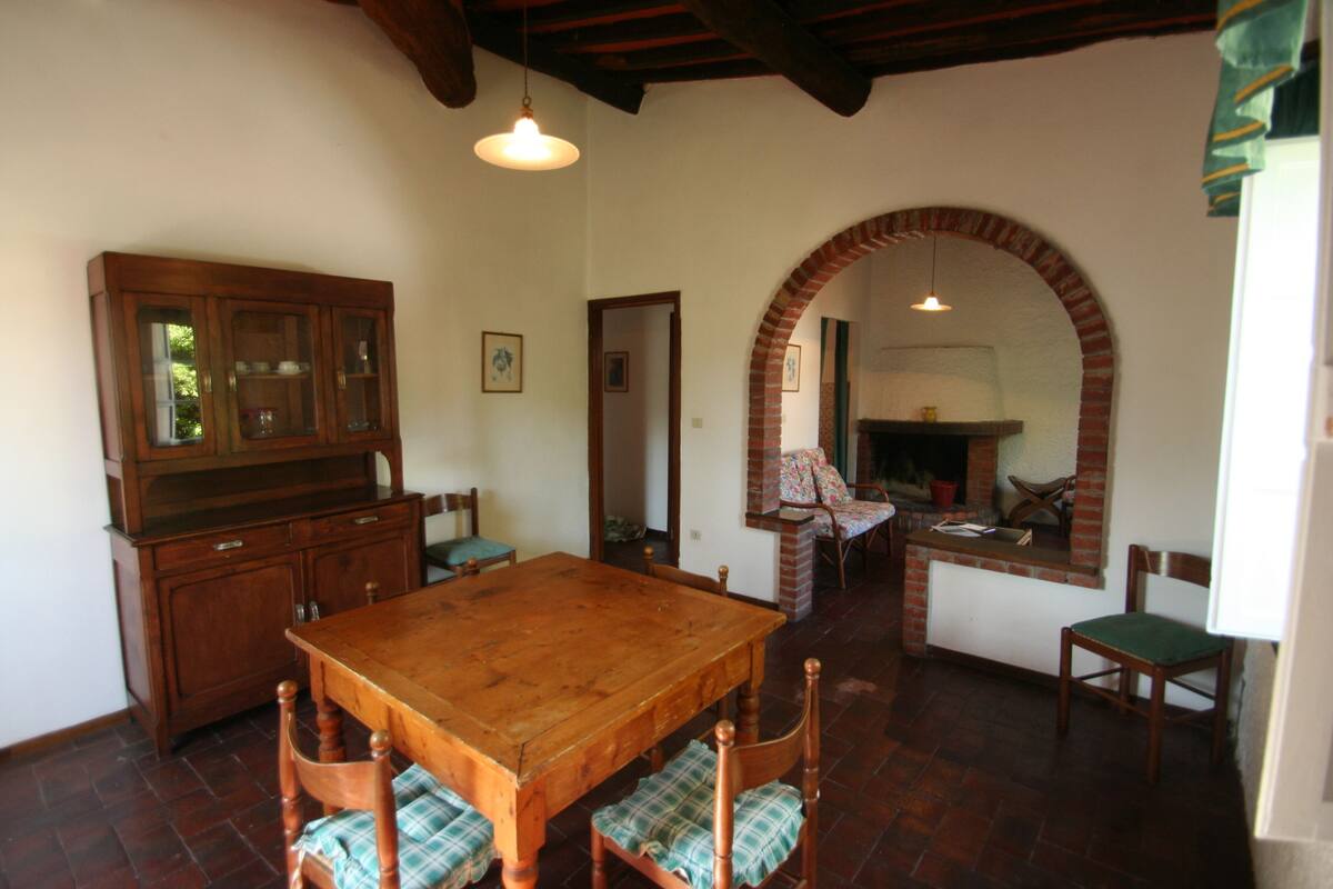 A dining area with a wooden table and chairs, a wooden cabinet, and a brick fireplace.