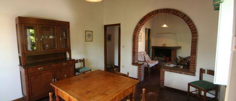 A dining area with a wooden table and chairs, a wooden cabinet, and a brick fireplace.