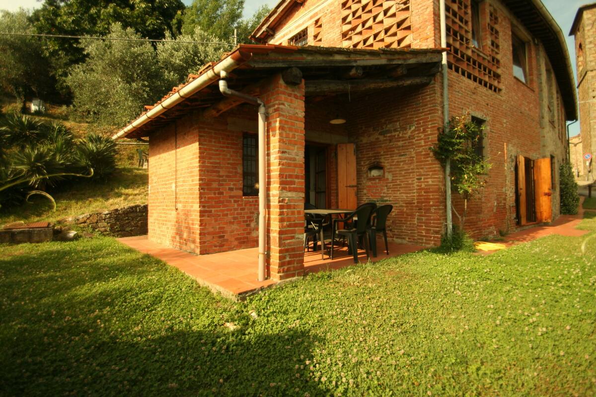 A brick house with a covered patio and a table and chairs outside.