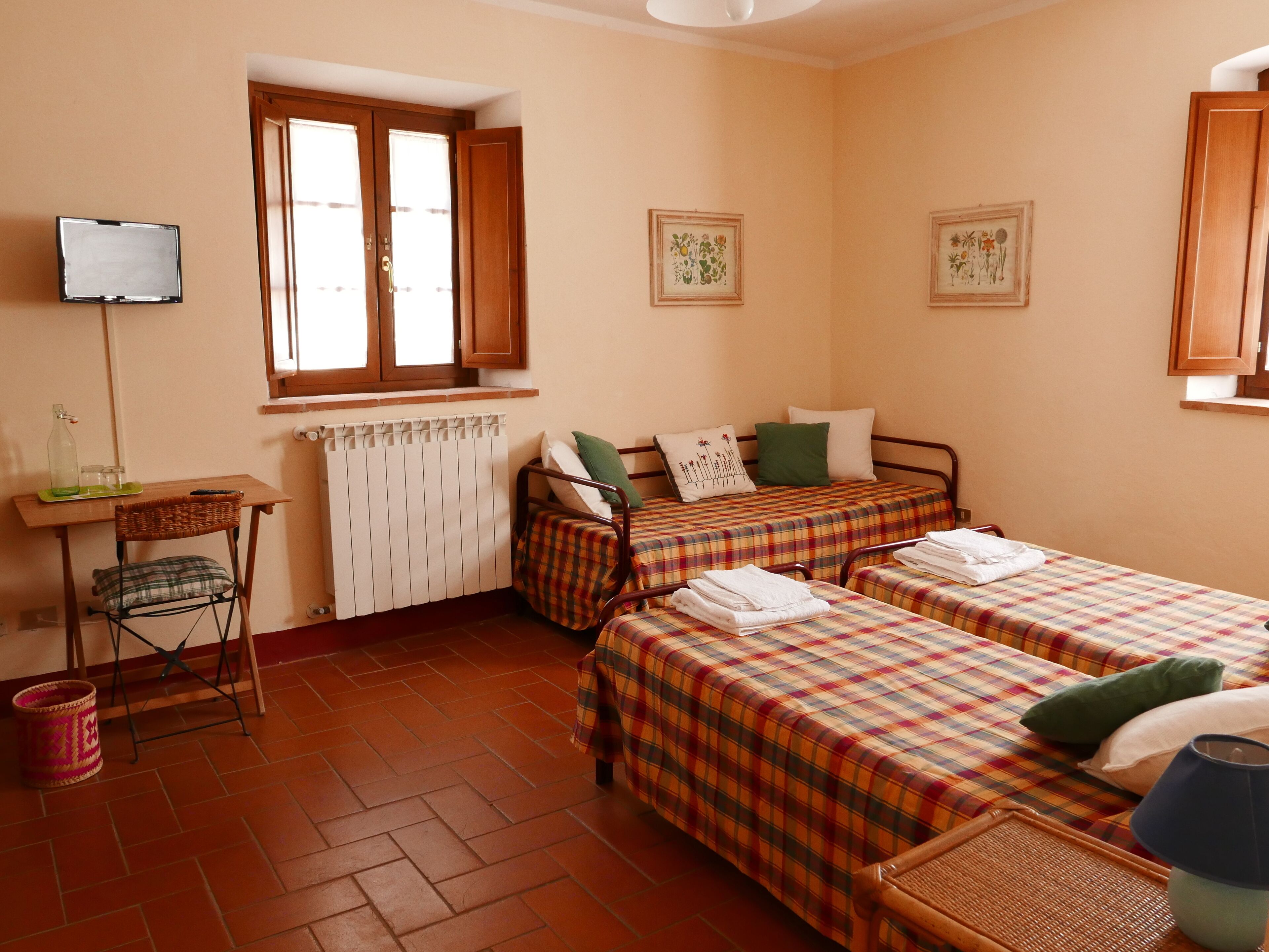 Una habitación con dos camas, un escritorio, una silla y un radiador.