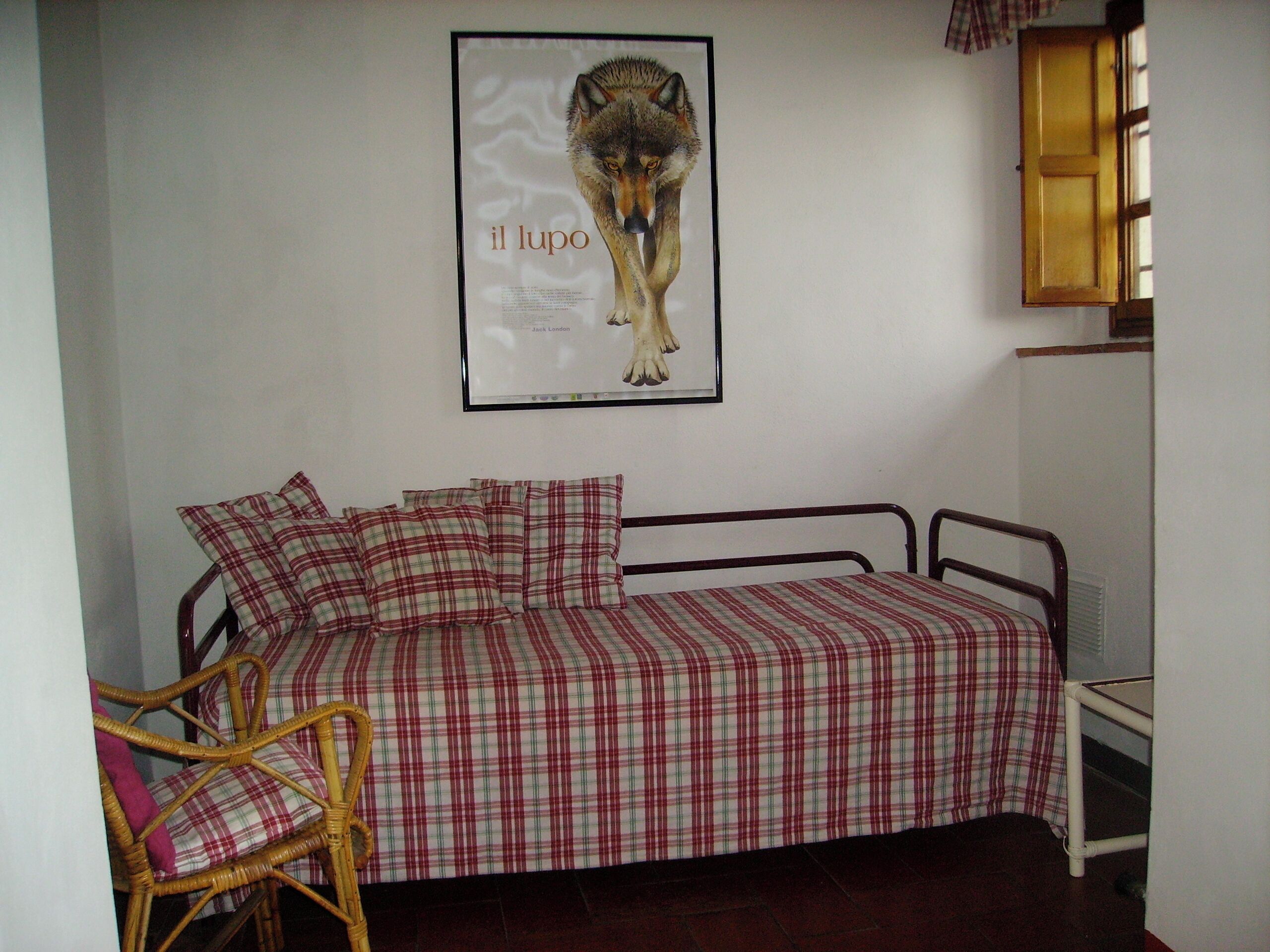 Ein Schlafzimmer mit einem Bett, einem Sessel und einem Bild eines Wolfs im Rahmen an der Wand.