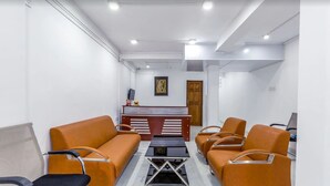 A waiting area with orange sofas, a reception desk, and a framed picture on the wall. - Metro Port City Hotel (Colombo)