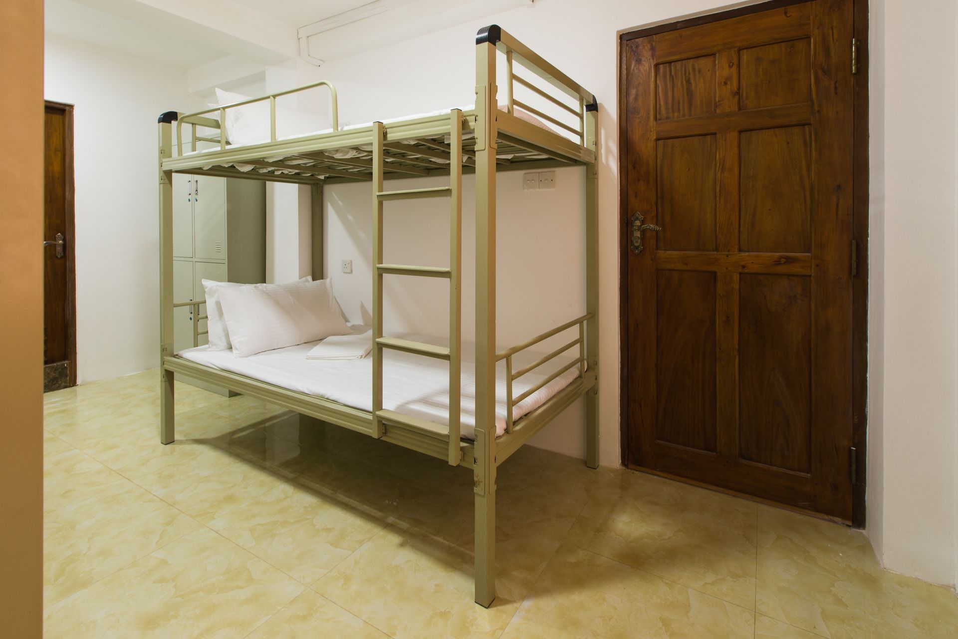 A bunk bed with a wooden door and a tiled floor.