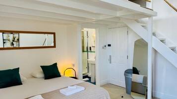 A bedroom with a bed, a mirror, a staircase, and a bathroom visible through an open door.