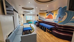 A restaurant with a modern interior, featuring a long counter with blue tables and a seating area with cushioned benches. - Reef Lodge (Newquay)