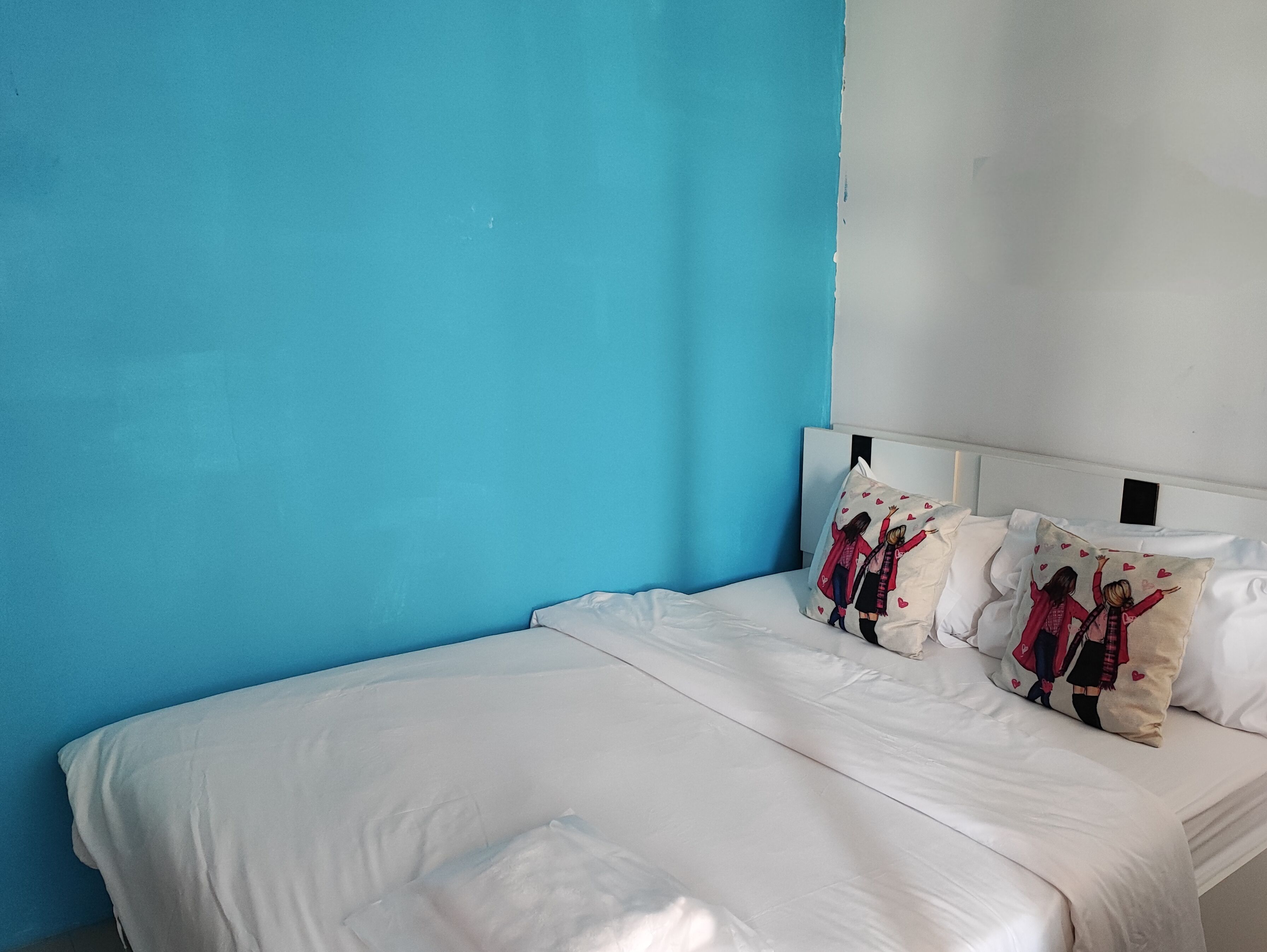 A bed with white bedding and two decorative pillows with a heart pattern.