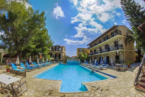 Una piscina al aire libre, sombrillas, sillones reclinables de piscina