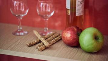 Un tavolo di legno con una bottiglia di vino, due bicchieri da vino vuoti e due mele.