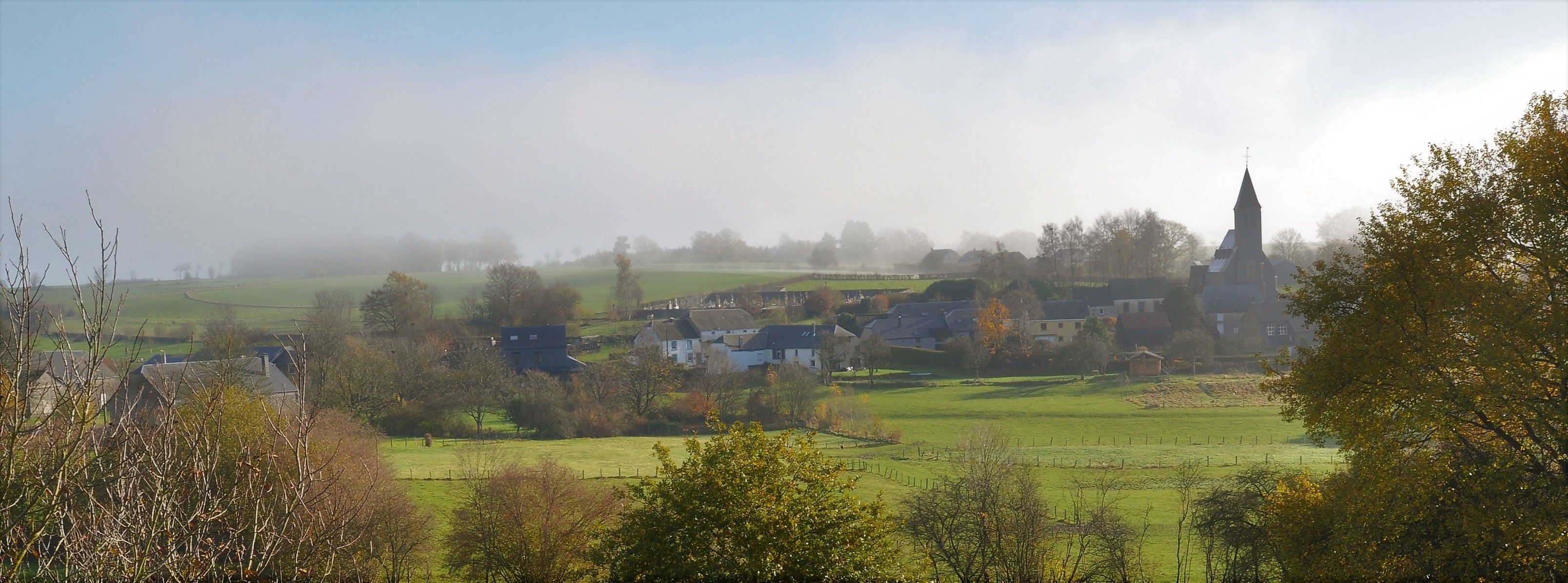 A rural village with houses, a church, and open fields.