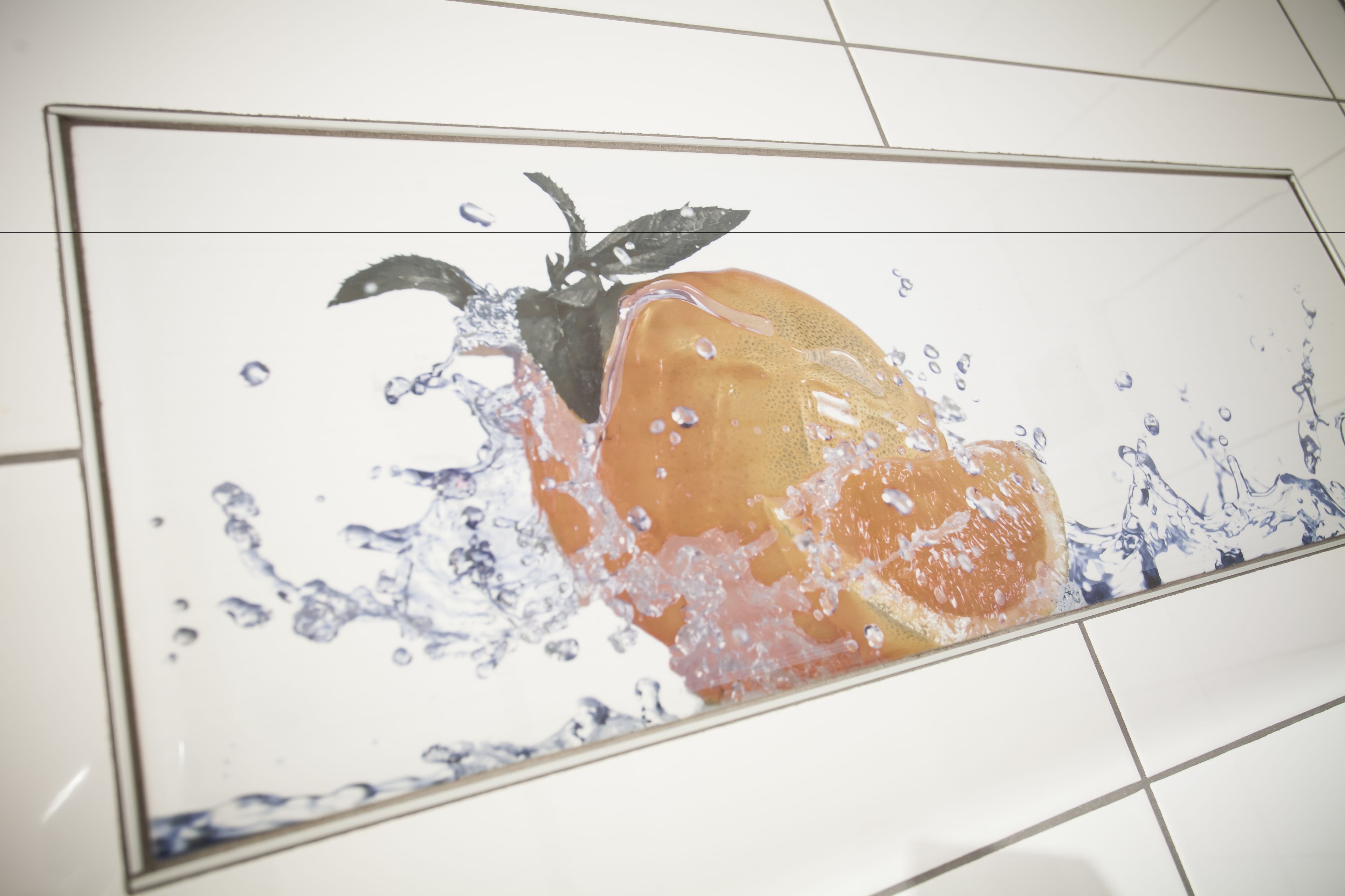 Un piso de baldosas con un charco de agua y una fruta.
