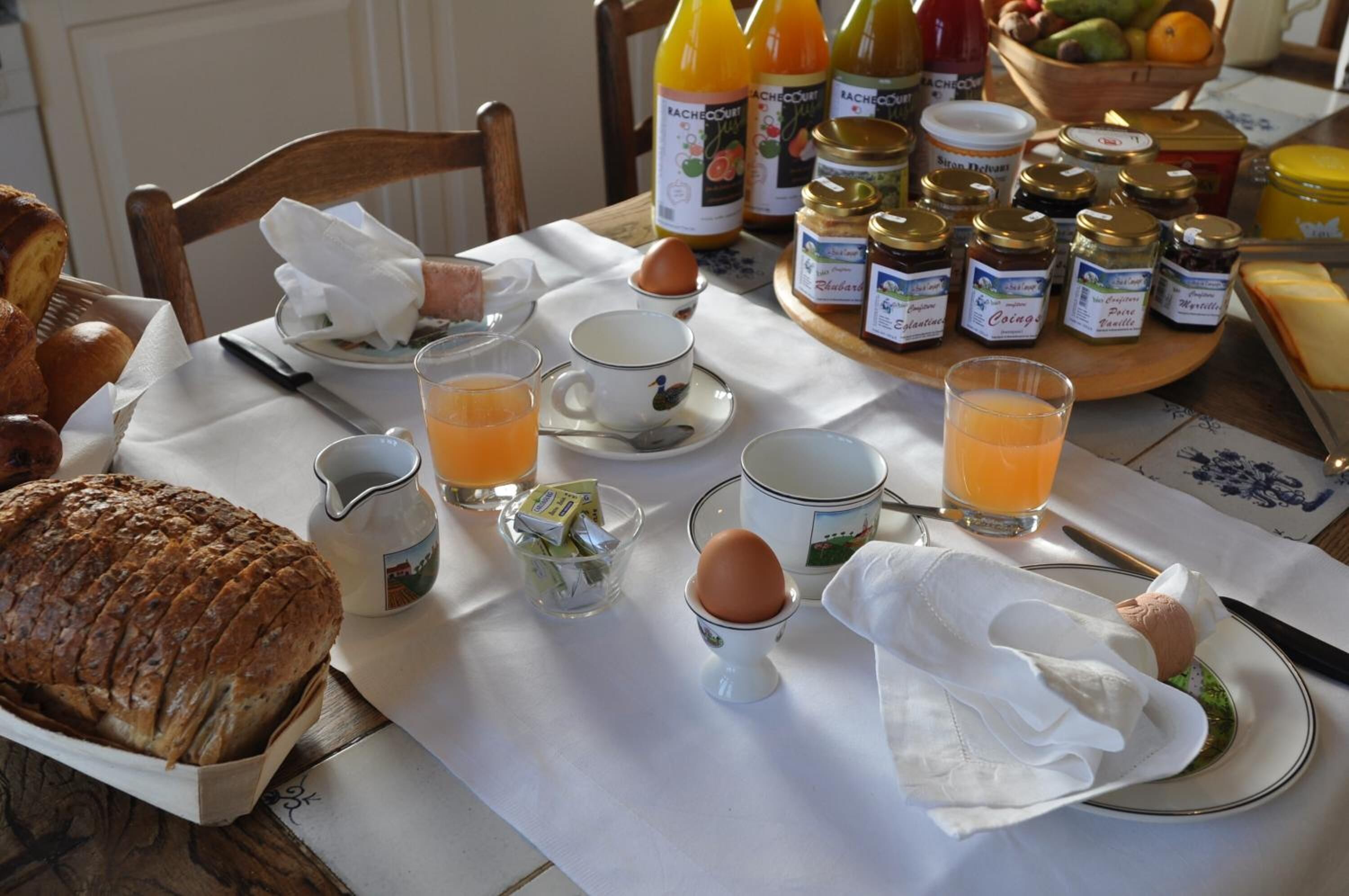 A breakfast table with bread, eggs, juice, and condiments.