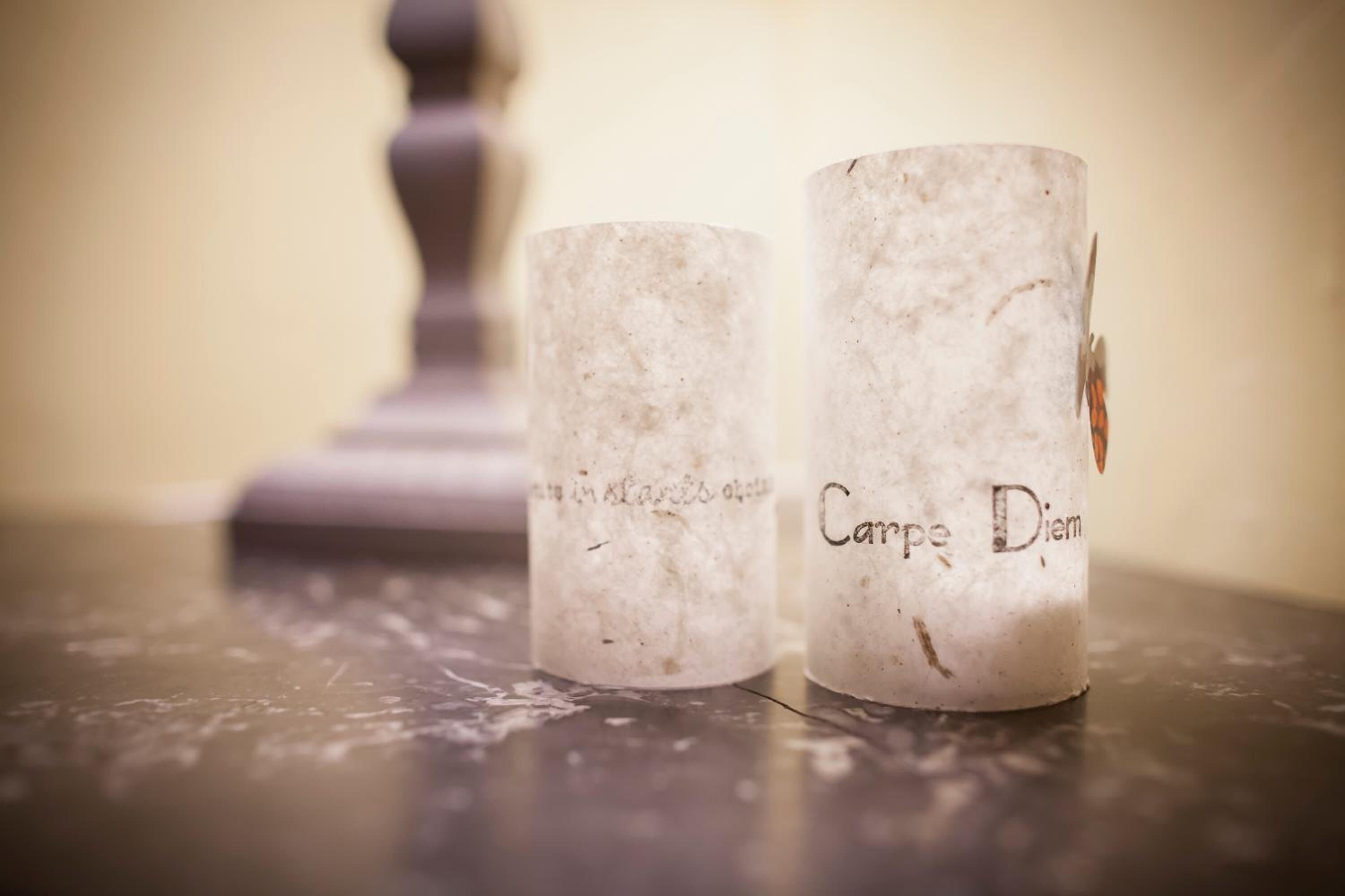 Two candle holders with inscriptions on a marble surface.