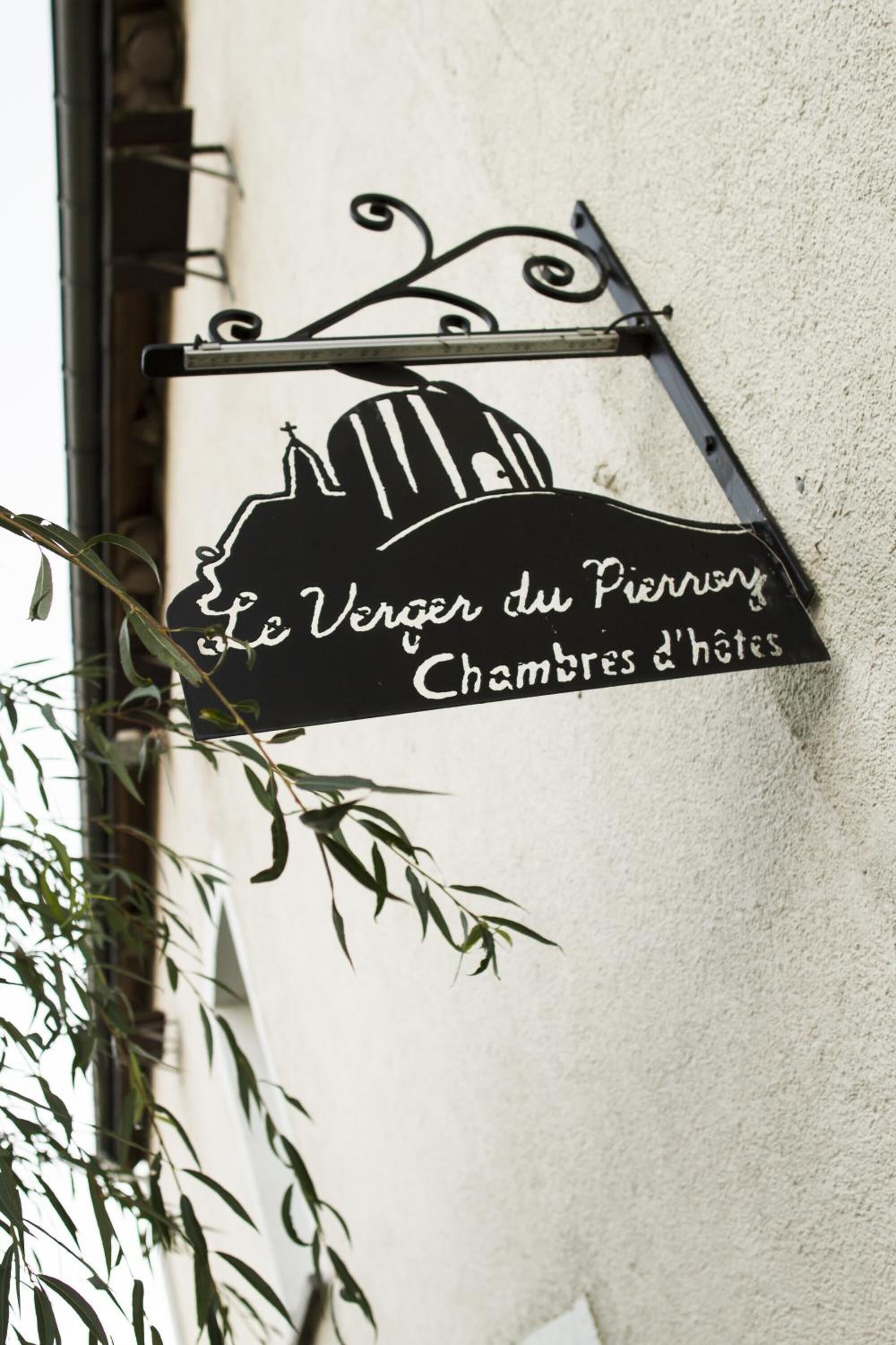 A black sign with white text and a silhouette of a building, hanging on a wall.