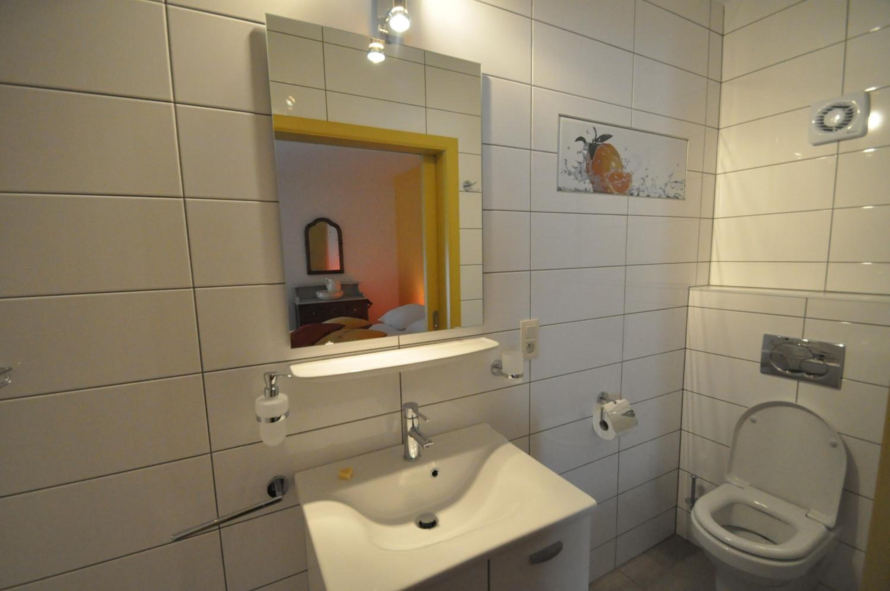 A bathroom with a white sink, mirror, and toilet.