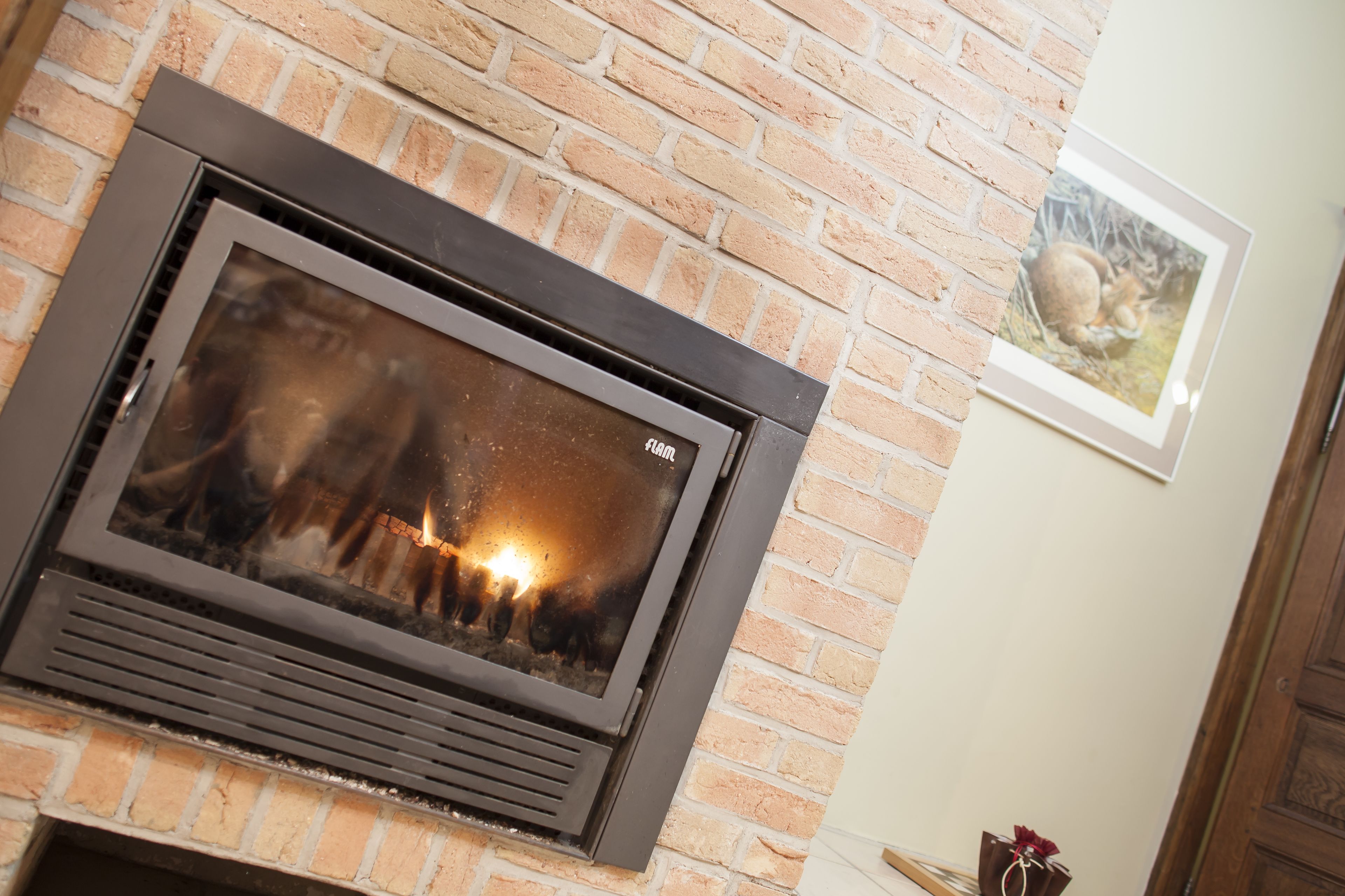A fireplace with a glass front, set in a brick wall.