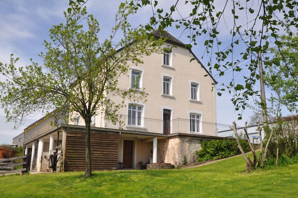 Ein zweistöckiges Gebäude mit Balkon, überdachter Veranda und Steinunterbau.