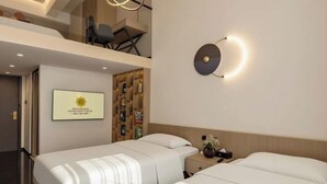 A hotel room with two beds, a wall-mounted light fixture, a bookshelf, and a framed picture on the wall. - Zhangjiakou International Hotel (Building B ) (Zhangjiakou)