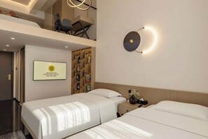 A hotel room with two beds, a wall-mounted light fixture, a framed certificate, and a bookshelf.