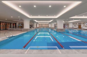 Una gran piscina interior con carriles bien definidos, rodeada de un diseño moderno con techos altos e iluminación brillante.