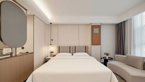 A modern hotel room with a large bed, a sofa, a desk, and a large mirror. - Zhangjiakou International Hotel (Building B ) (Zhangjiakou)