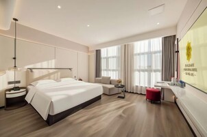 Una habitación de hotel moderna con una cama grande, un sofá, una mesita y un escritorio.
