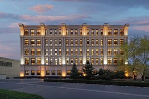 Un edificio de varios pisos con fachada simétrica, ventanas regularmente distribuidas y una entrada central.