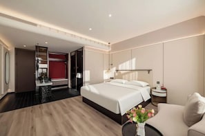 Et moderne hotelværelse med en stor seng, et siddeområde, et skrivebord og en rød accentvæg.