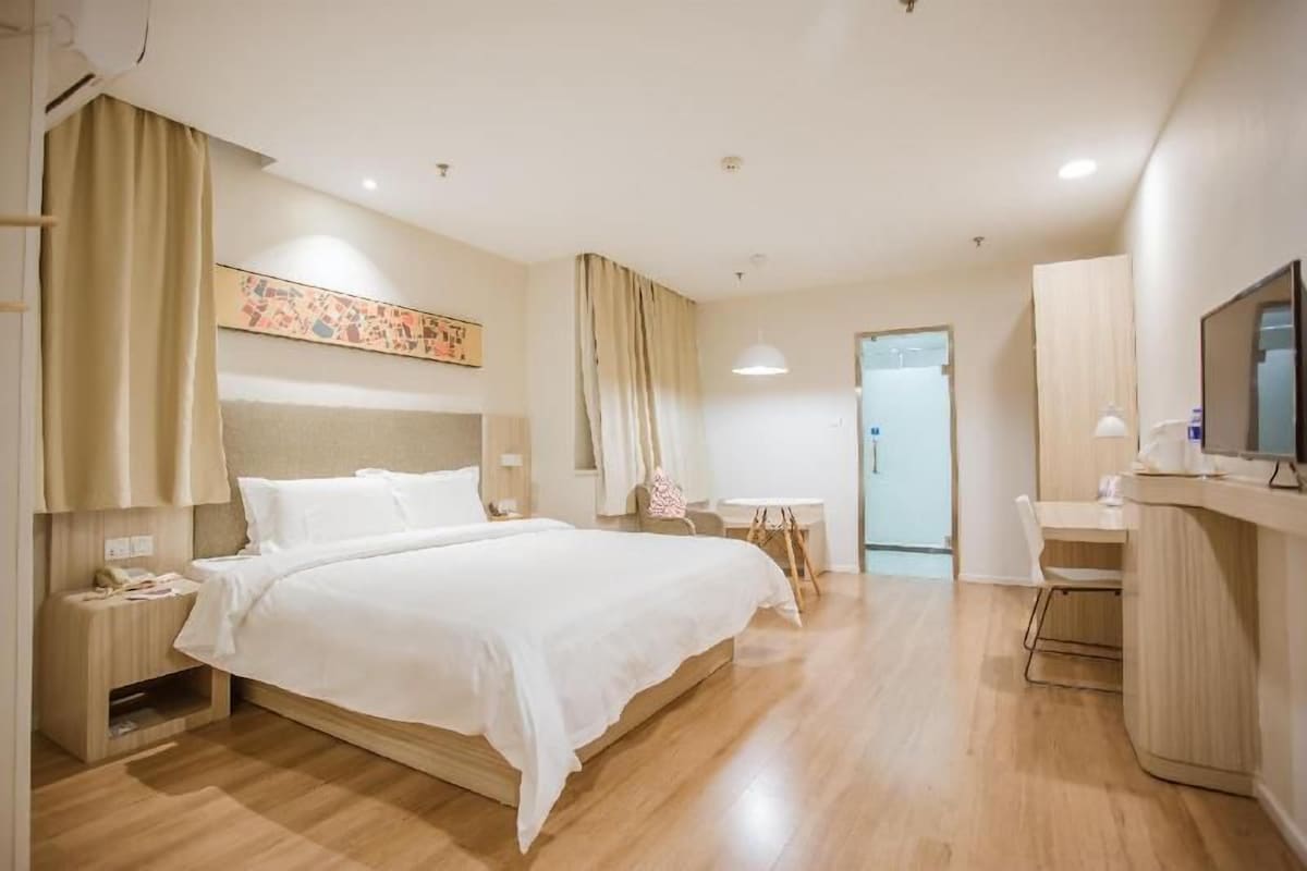 Una habitación de hotel con cama, mesita de noche, lámpara y televisión.