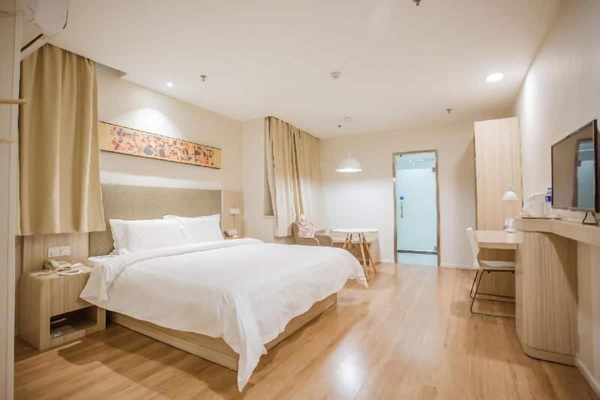 A hotel room with a bed, bedside table, lamp, and a TV.