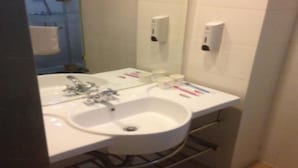 A bathroom with a white sink, mirror, and two towel dispensers.