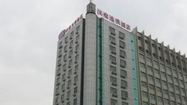 A multi-story building with a prominent vertical green stripe, a sign with Chinese characters, and a billboard.