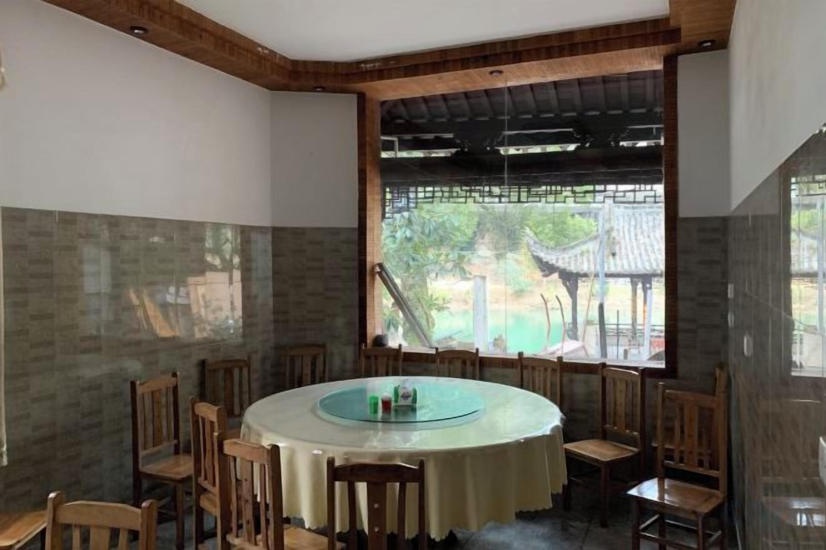 A dining area with a round table, chairs, and a view of greenery outside.