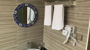 Une salle de bain avec un miroir rond, des serviettes blanches, un sèche-cheveux et un porte-serviettes.