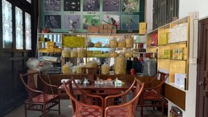 Une pièce avec une table et des chaises en bois, entourée d  ’étagères remplies de divers objets.