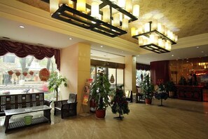 A hotel lobby with a reception desk, seating area, and potted plants. - Jingxin Business Hotel (Xishan Road Branch) (Guilin)