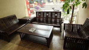 A room with a wooden sofa set, a coffee table, and a potted plant. - Jingxin Business Hotel (Xishan Road Branch) (Guilin)