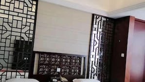 A hotel room with two beds, a decorative headboard, and a partition with intricate designs. - Jingxin Business Hotel (Xishan Road Branch) (Guilin)