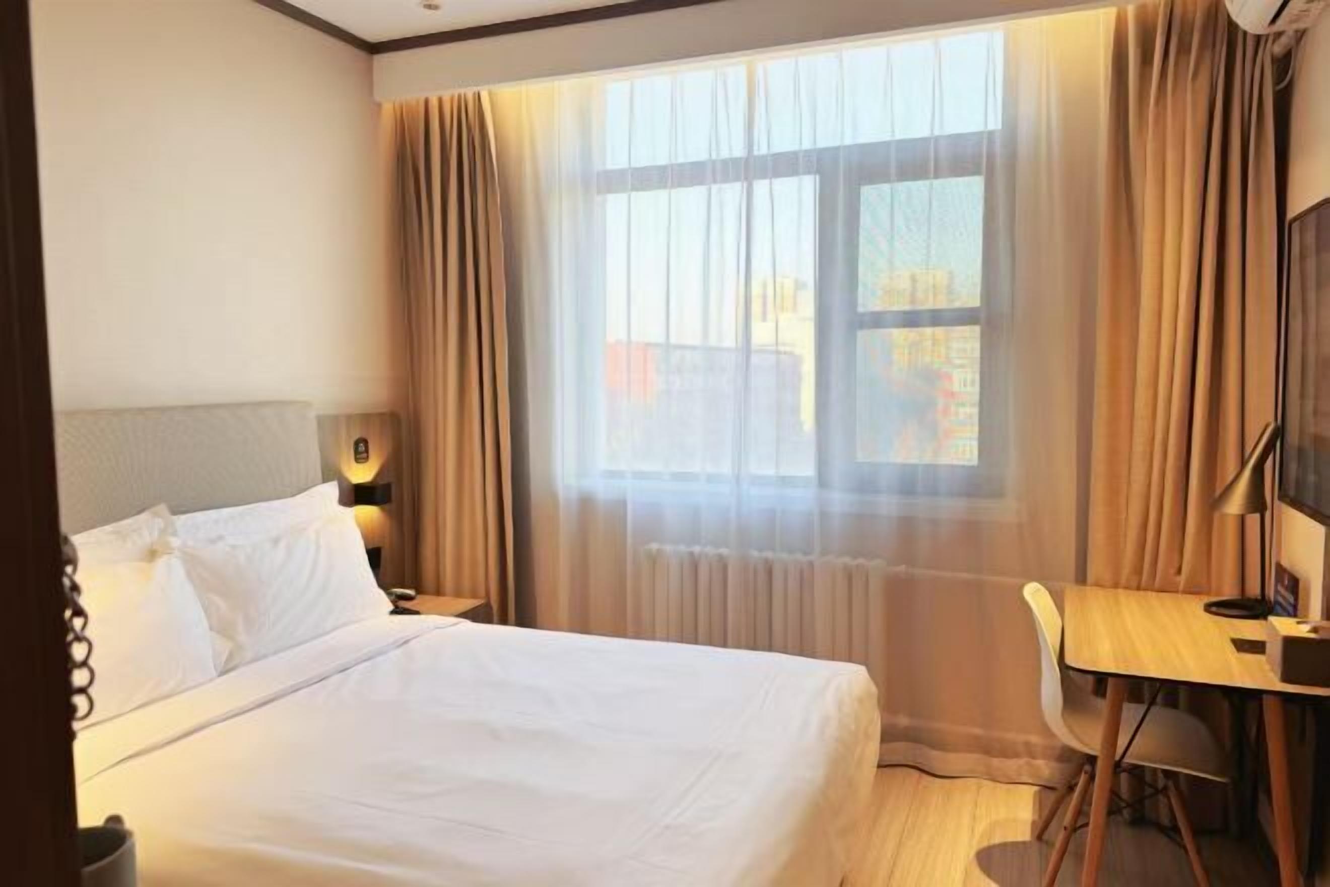 Une chambre d’hôtel avec un lit, un bureau et une chaise.
