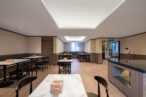 A modern hotel dining area with tables, chairs, and a counter. - HanTing Hotel (Communication University of Beijing Subway Station) (Beijing)