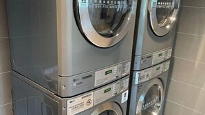 A stack of LG washing machines with visible control panels and safety warnings.