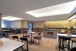 A modern hotel lobby with a dining area, a reception desk, and a kitchen visible in the background. - HanTing Hotel (Communication University of Beijing Subway Station) (Beijing)