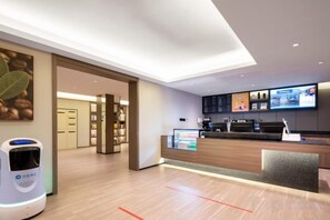 A modern hotel lobby with a reception desk, digital information screens, and a self-service kiosk. - HanTing Hotel (Communication University of Beijing Subway Station) (Beijing)