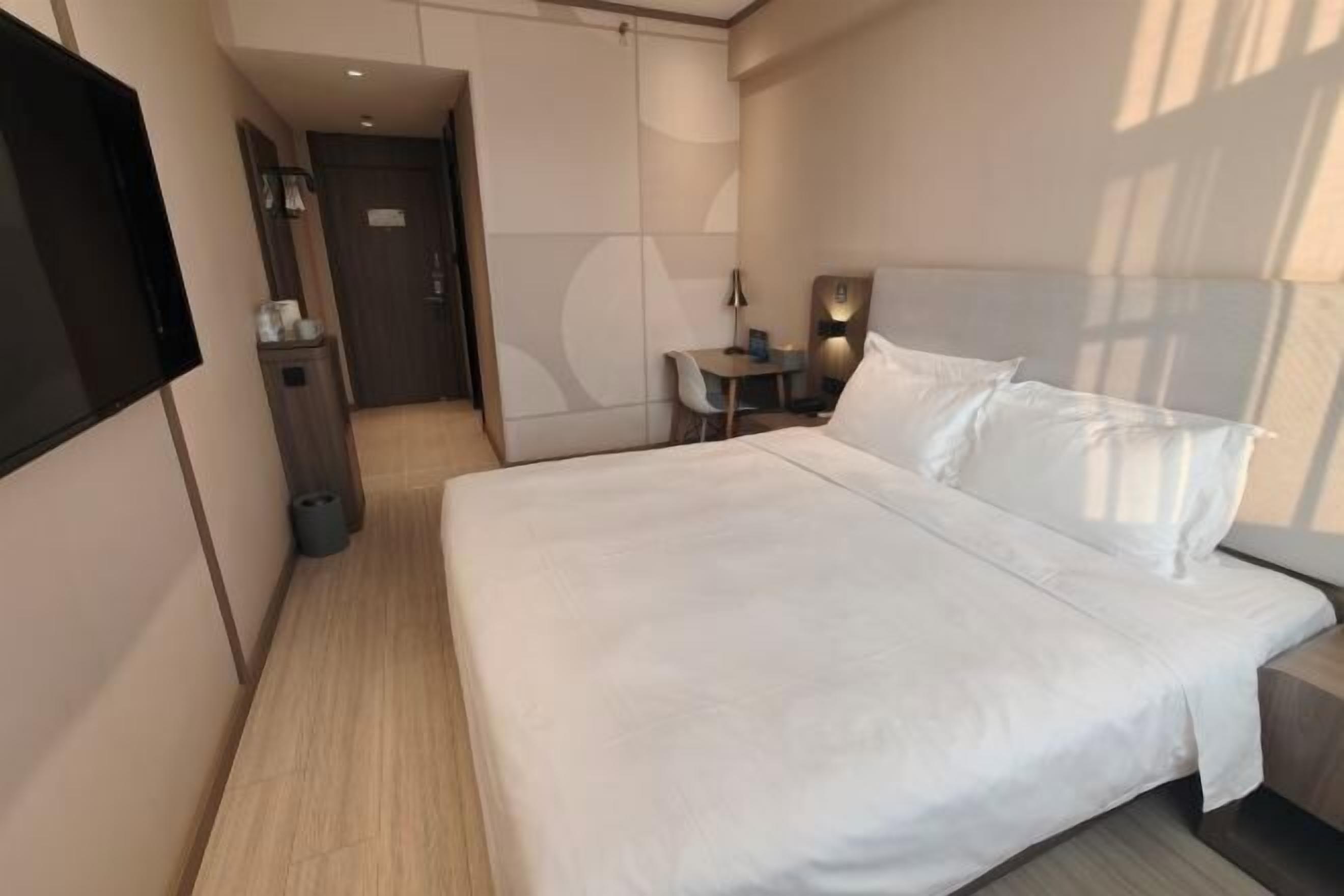 A modern hotel room with a large bed, a desk, and a chair.
