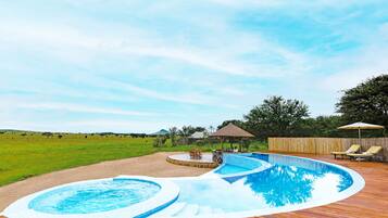 Una piscina al aire libre, sombrillas, sillones reclinables de piscina