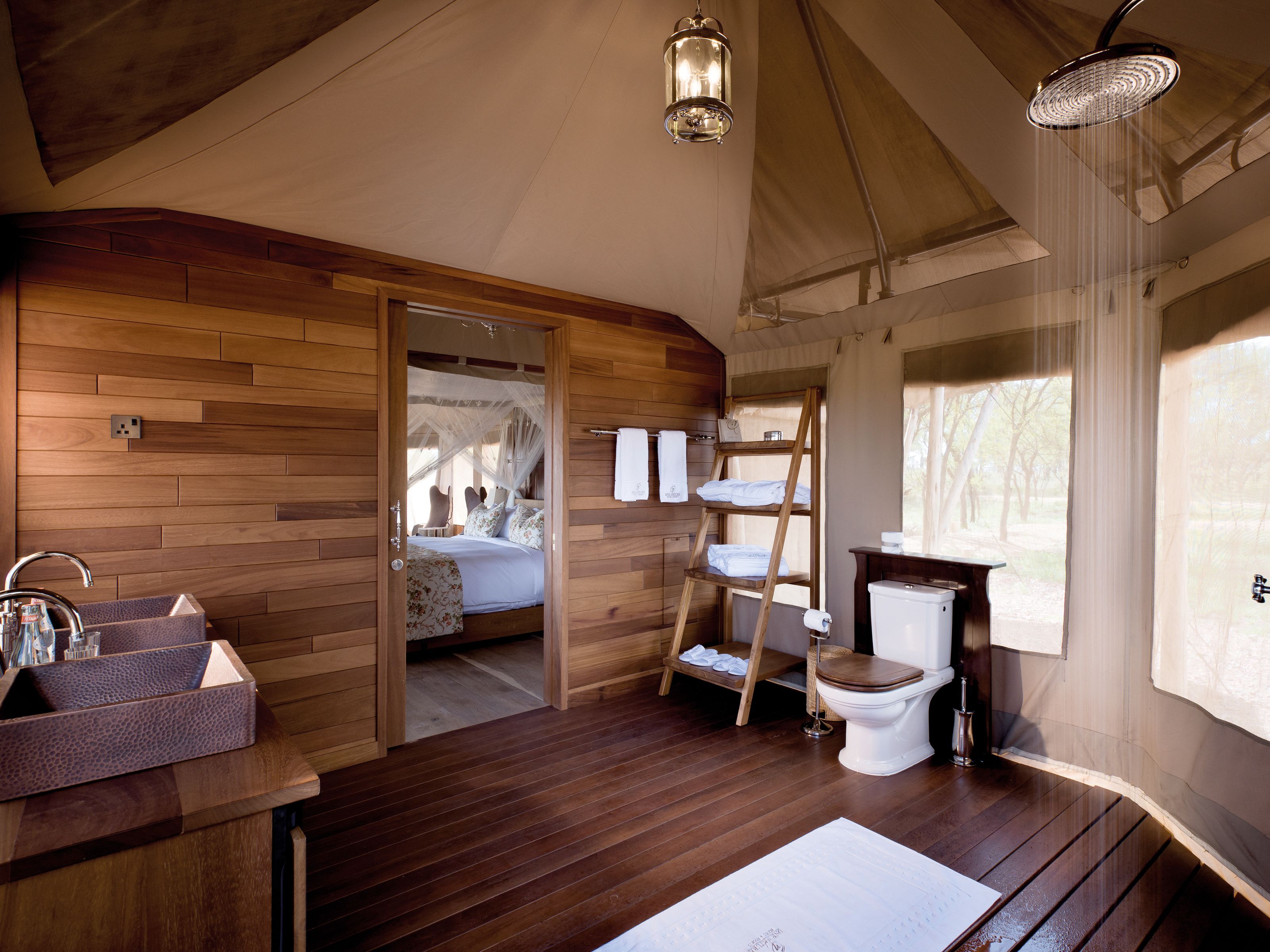 A wooden-floored bathroom with a sink, toilet, and a shelf with towels.