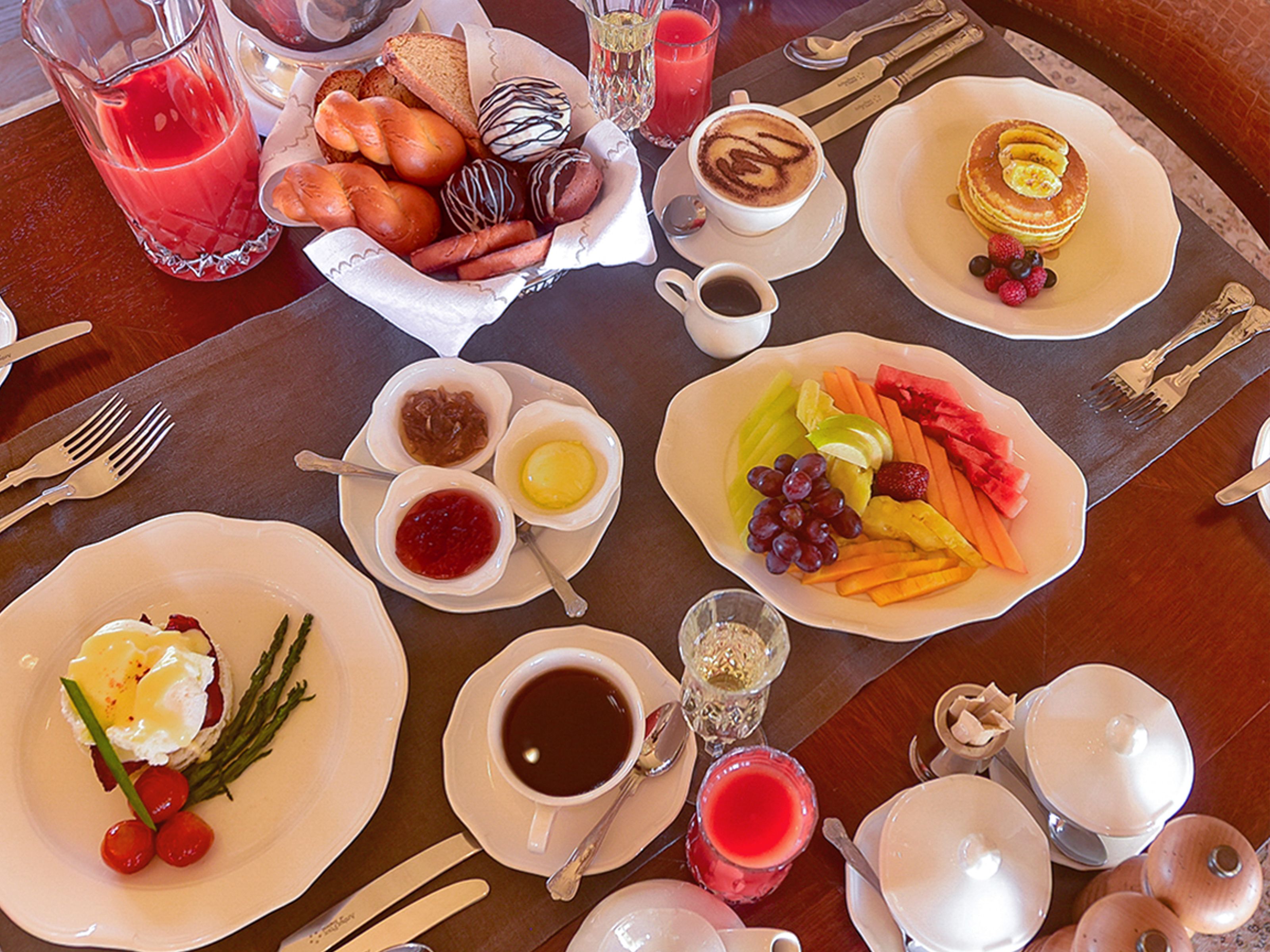 Ein Frühstücksbuffet mit verschiedenen Speisen, darunter Toast, Gebäck, Obst und Getränke.