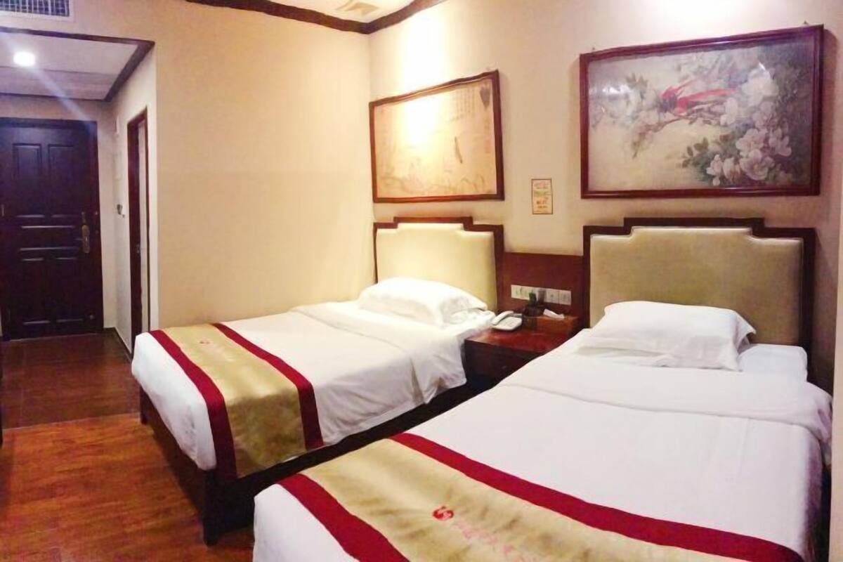 A hotel room with two beds, a nightstand, a telephone, and a painting on the wall.