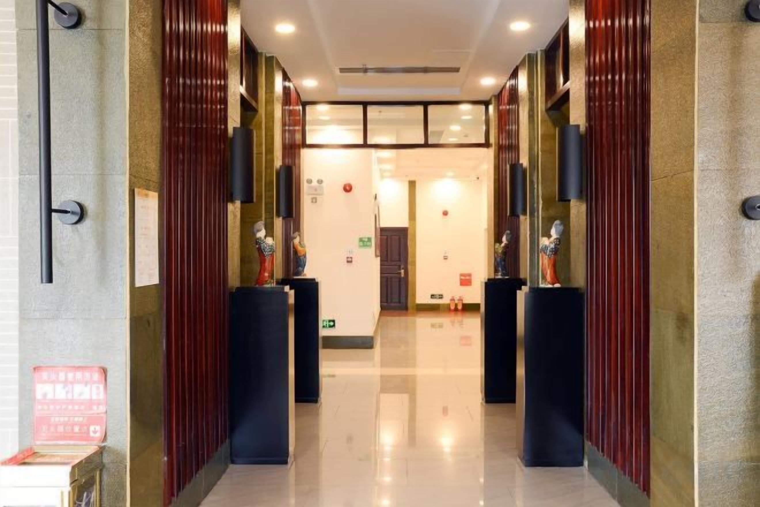 A hotel lobby with a polished floor, dark wooden panels, and black columns.