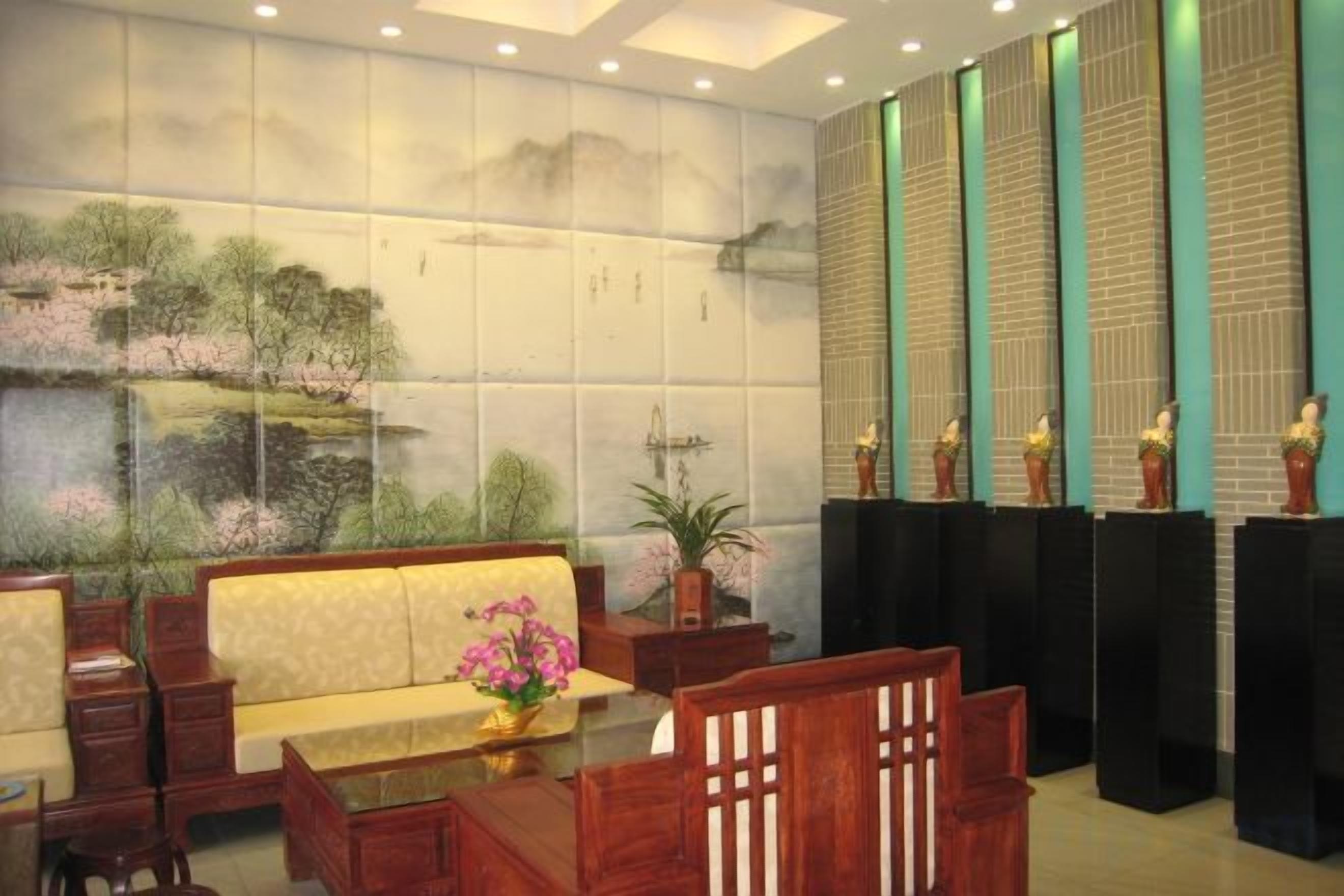 A reception area with a sofa, chairs, a table with a vase, and a wall with a mural.